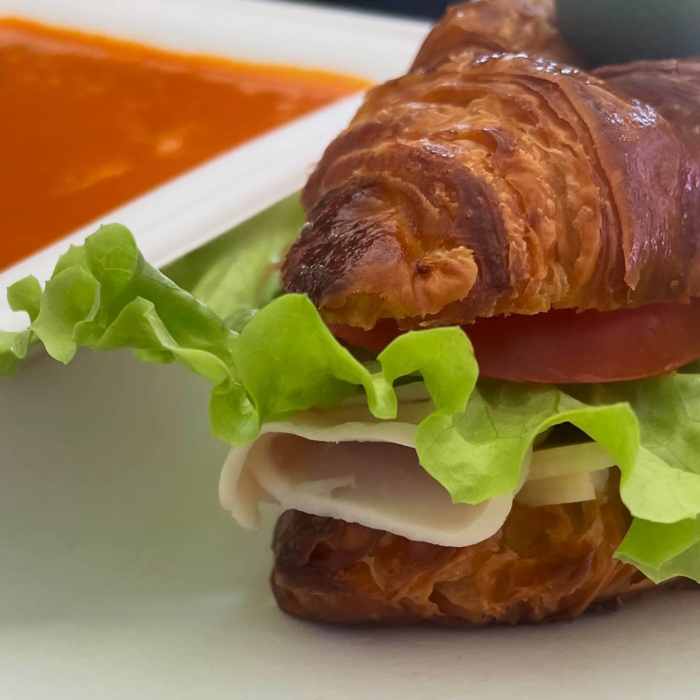sliced turkey on a croissant with leafy lettuce